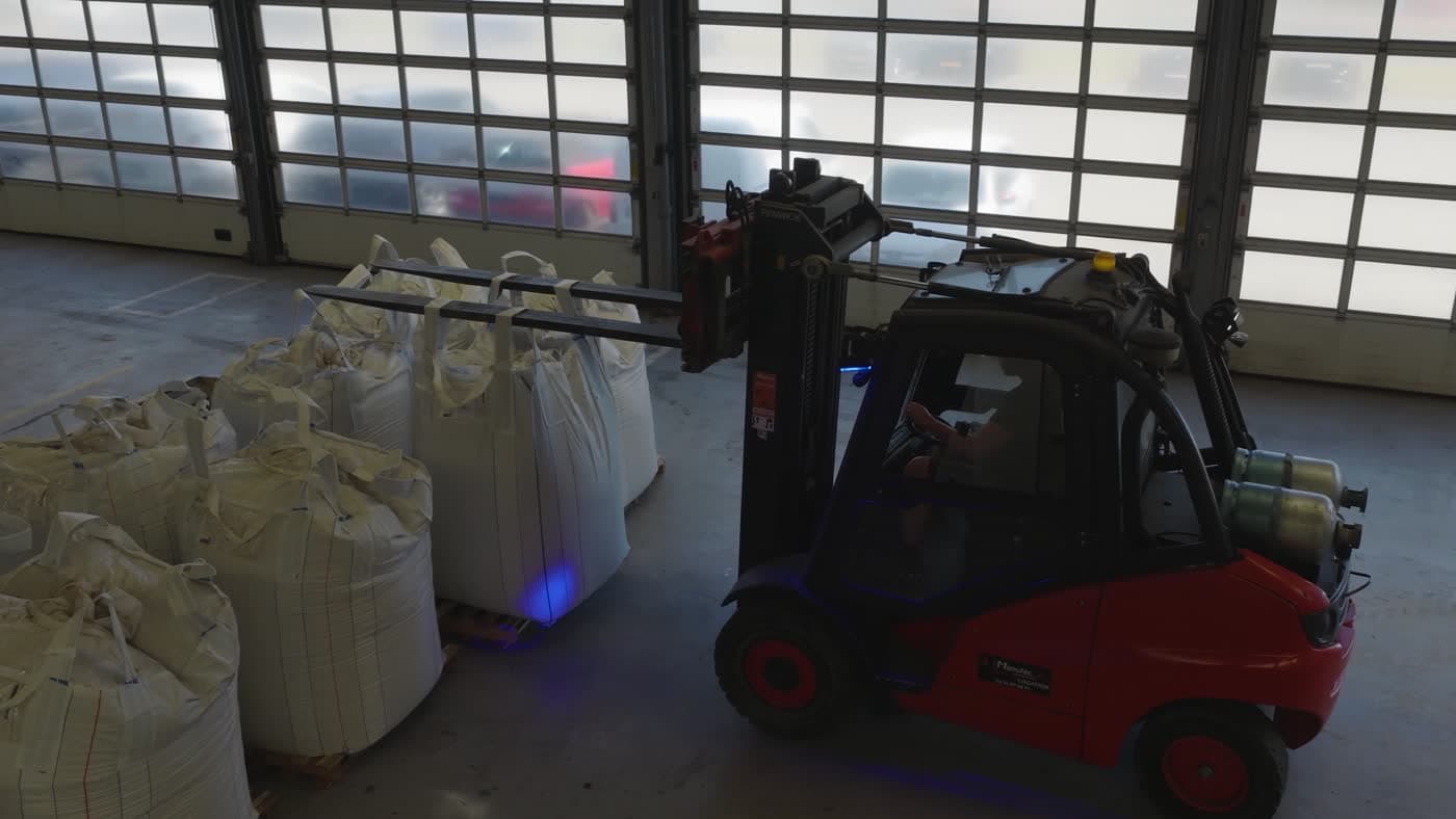 Big bags de matériaux et chariot élévateur dans un dépôt